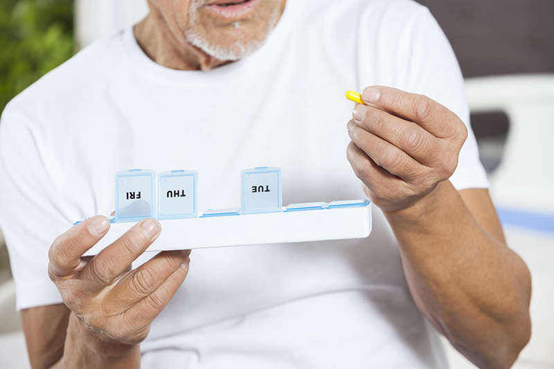 A man manages his medications in outpatient treatment by using a pill box to organize them.